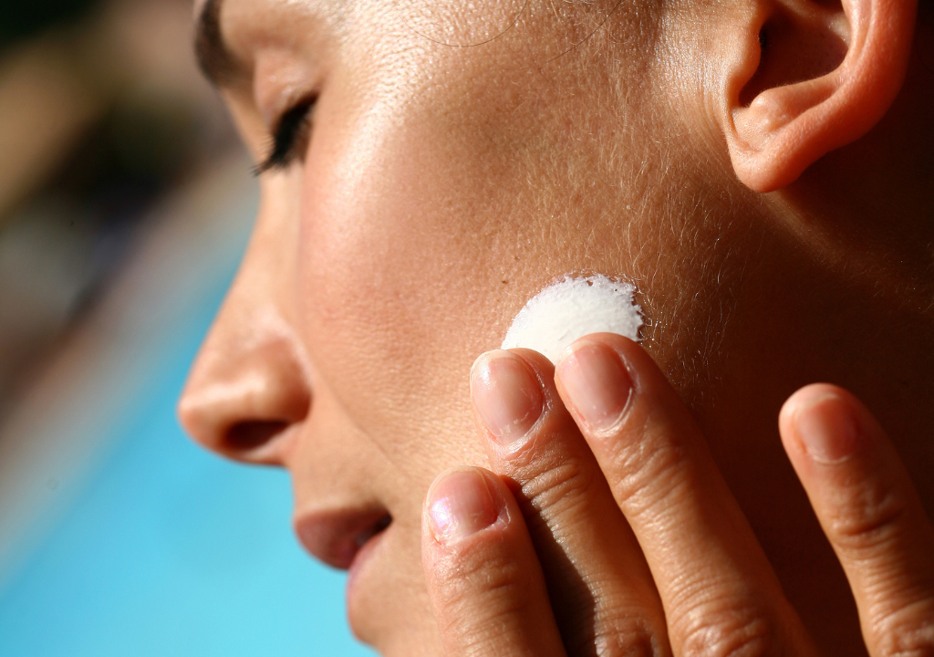 Woman applying skincare in the sun