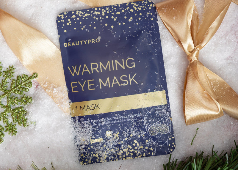 Warming eye mask with gold ribbons and decorative elements on a textured surface