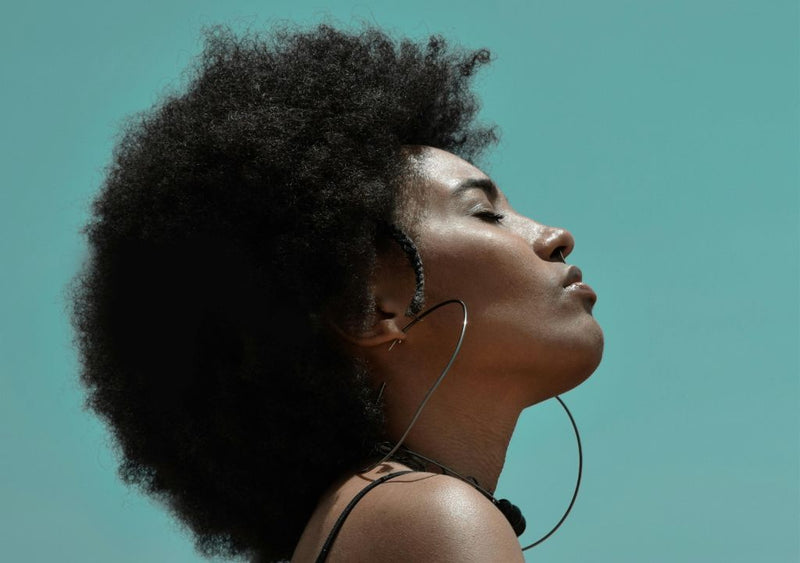 lady with black skin looking up at a sunny sky