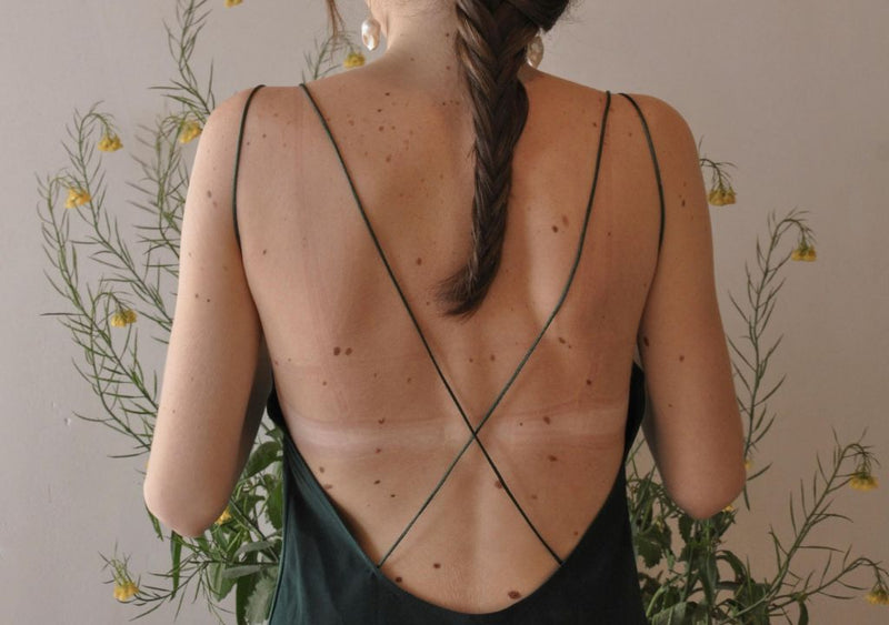 Lady in strappy dress stood in front of flowers