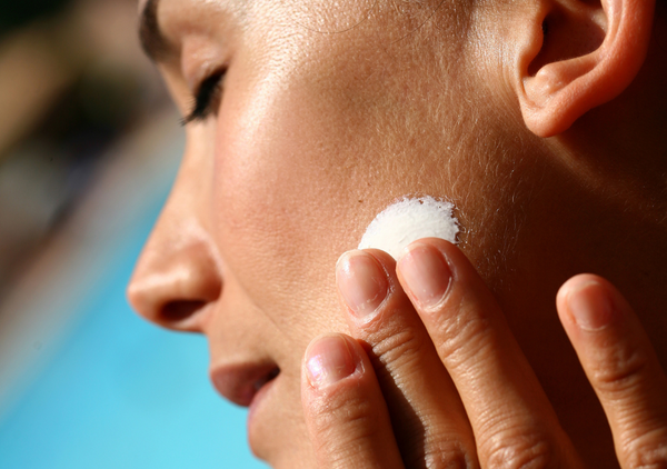 Woman applying skincare in the sun