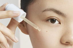 a closeup of a women applying the elixir to her face