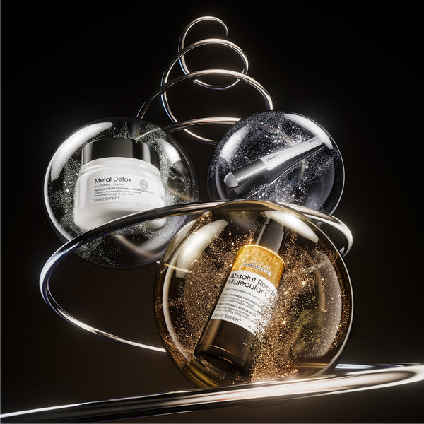 Two skincare products displayed inside clear spherical containers with metallic rings and glitter on a black background. One container holds a white jar labeled Metal Detox, and the other holds a brown bottle with a gold label and white text.