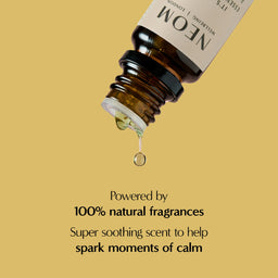 Bottle of NEOM essential oil with a droplet on a beige background