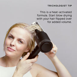 A woman blow-dries her hair using a black hair dryer with a brush attachment, shown against a light gray background with promotional text in the upper right.