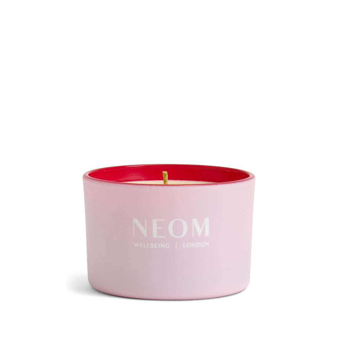 Pink NEOM candle with a red interior on a white background