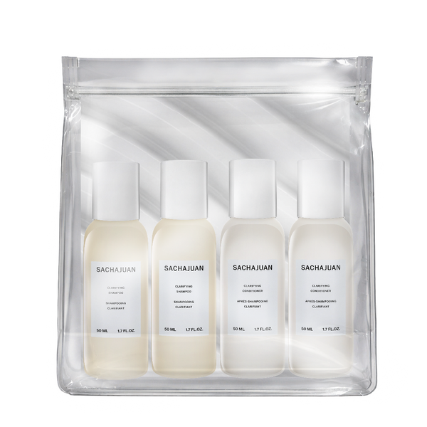 A clear zip pouch containing four small white bottles of Sacha Juan haircare products, photographed on a clean white background.