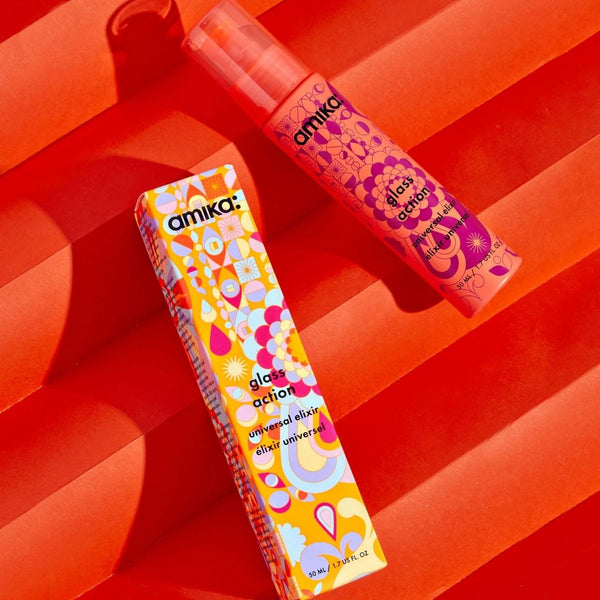 Two colorful cosmetic bottles with 'amika' branding on a red background