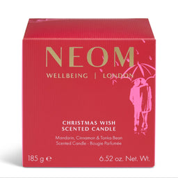 A red square box for a scented candle with gold and white text reading NEOM WELLBEING | LONDON and CHRISTMAS WISH SCENTED CANDLE, plus a pink illustration of a couple under an umbrella on a white background.