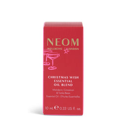A red rectangular box of NEOM Wellbeing 'Christmas Wish' Essential Oil Blend, featuring gold and white text and a cocktail glass illustration, set against a plain white background.