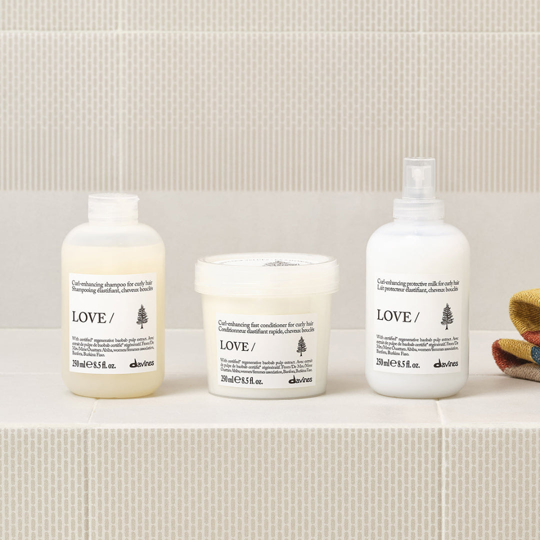 Three Davines hair care products on a textured surface with a neutral background