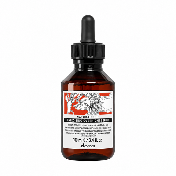 A 100 ml amber glass dropper bottle of Davines Naturastéc Energy+ Overnight Serum, featuring a black dropper cap and a white label with red and black graphics, on a solid white background.