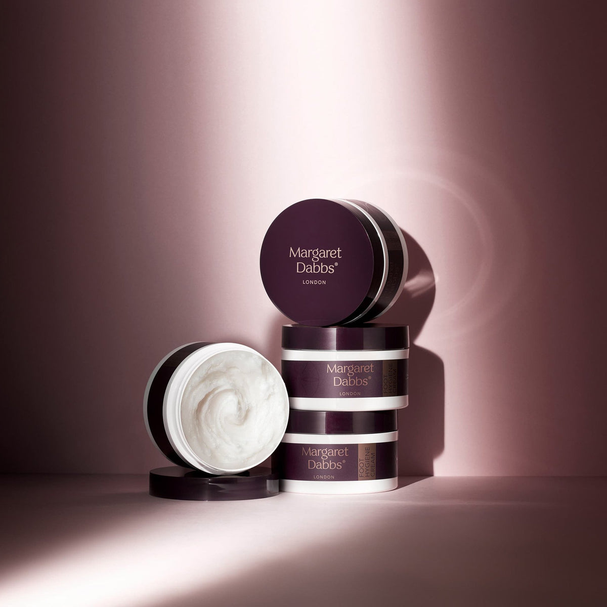 Skincare products with 'Margaret Dabbs' branding on a pink background
