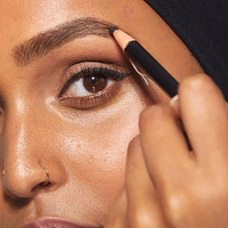 a closeup of a women applying the pencil