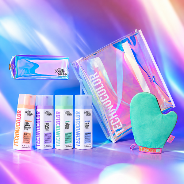 A beauty gift set from both sides featuring Technocolor hair products, including four spray bottles, a holographic makeup pouch, a large holographic tote bag, and a mint green silicone oven mitt, arranged on a vibrant, multicolored light streak background.