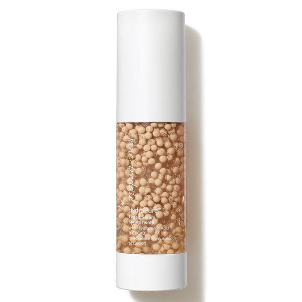 A cylindrical cosmetic bottle filled with beige microbeads, featuring a white cap and base, on a clean white background with a soft shadow.
