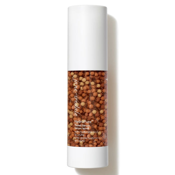 A cylindrical cosmetic tube with a white cap and base, featuring a clear center section filled with small brown and beige botanical beads. The tube is labeled 'pureveda' and 'hydroPure'.
