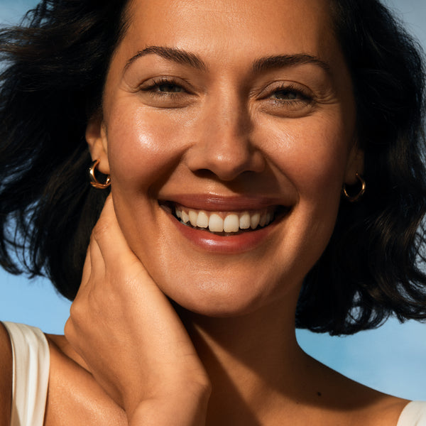 Woman with a bright smile against a clear blue sky