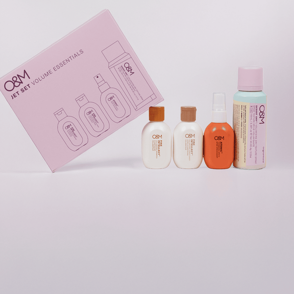 Set of Q&M hair care products with a pink box on a light gray background