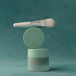 A jar of One De Vica Extraordinary Nail Mask with a matching brush and lid, displayed on a textured teal background.