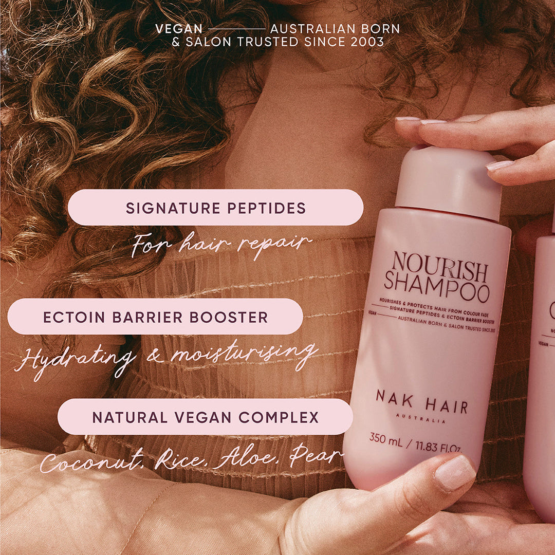 Person holding a NAK Hair shampoo bottle with product features displayed.