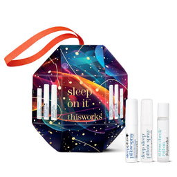 This is a sleep on it thisworks gift set featuring a colorful geometric hexagonal box with an orange ribbon handle, containing four white travel pillow spray vials, shown on a clean white background.
