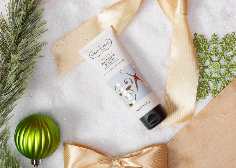 Hand cream with gold bow and festive decorations on a light background