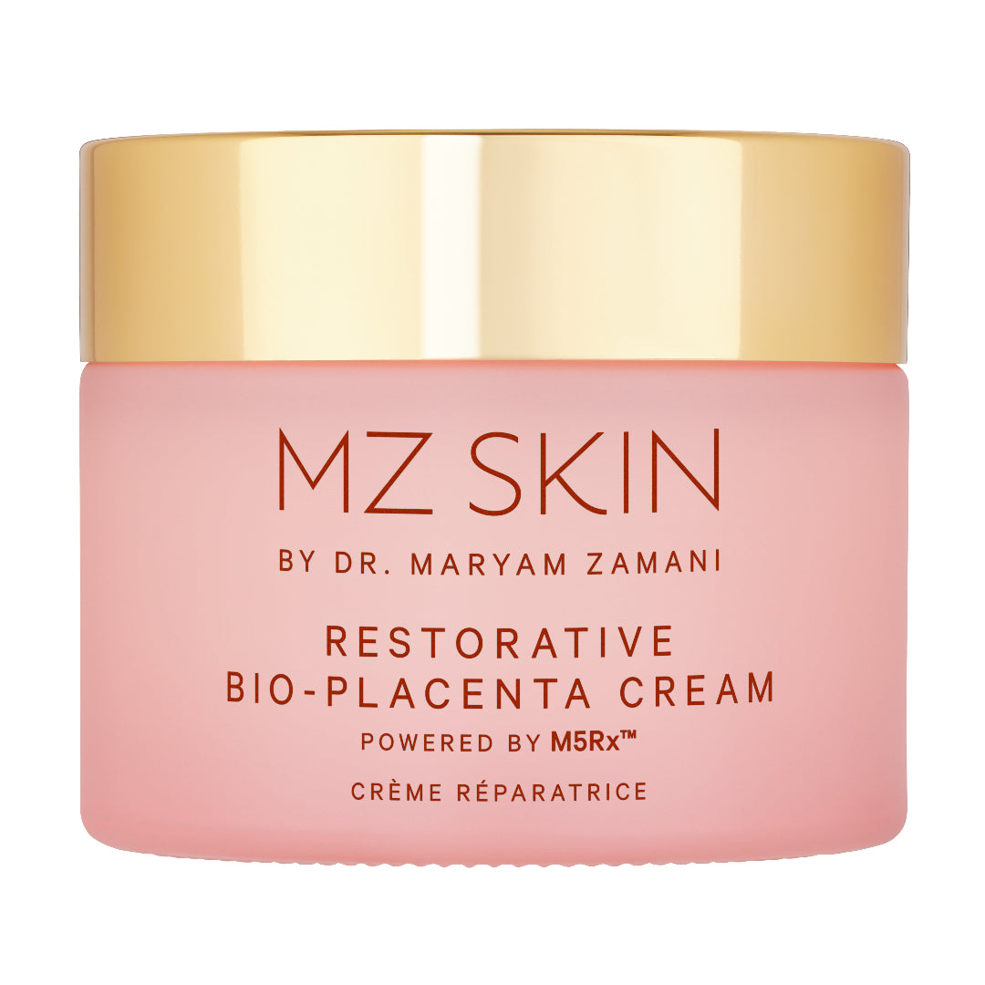 A pink cosmetic cream jar with a shiny gold lid, labeled 'MZ SKIN BY DR. MARYAM ZAMANI RESTORATIVE BIO-PLACENTA CREAM'.