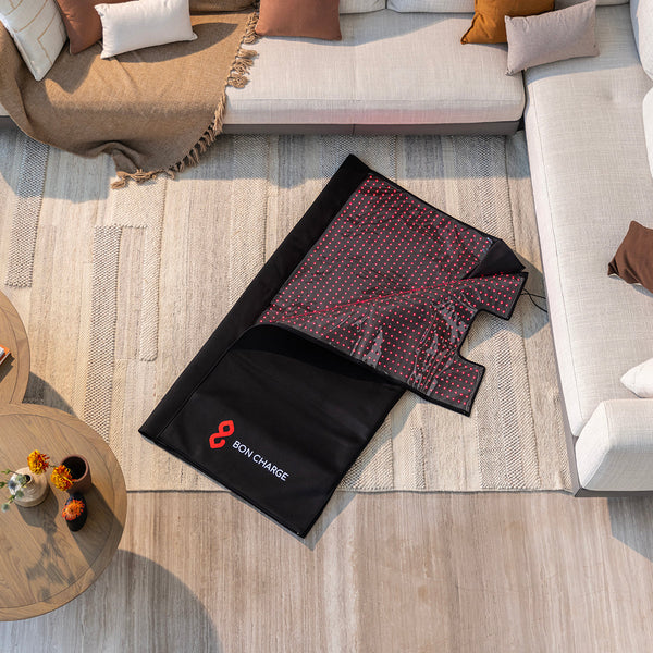 Two heating pads on a wooden floor with a sofa and coffee table in the background.