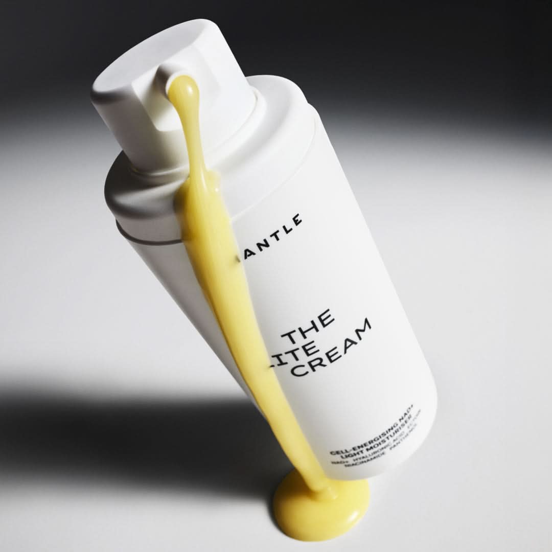 White bottle of 'The White Cream' with yellow cream being squeezed out on a gray background