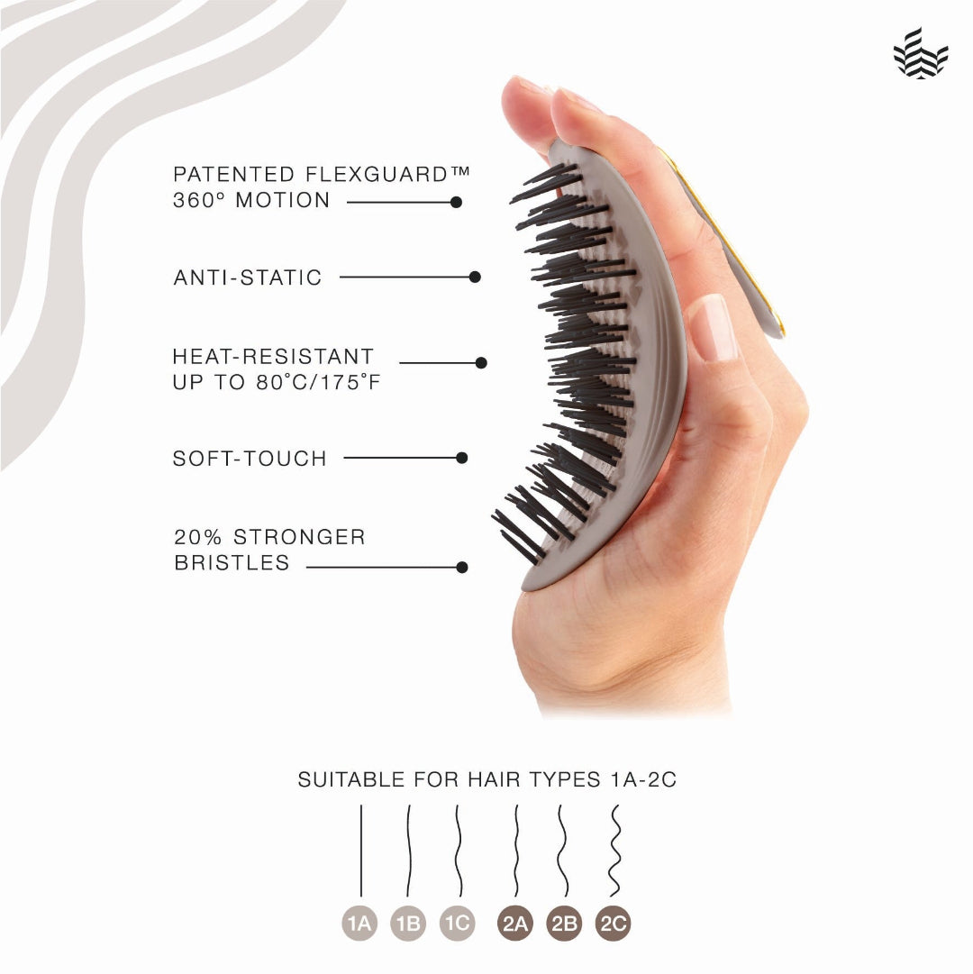 A hand holds a flexible hairbrush with black bristles and a gray handle, shown on a white background with feature callouts and a hair type suitability diagram.
