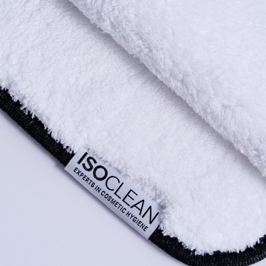 Close-up of a white plush microfiber cloth with a black stitched edge and a white brand tag reading ISOCLEAN.