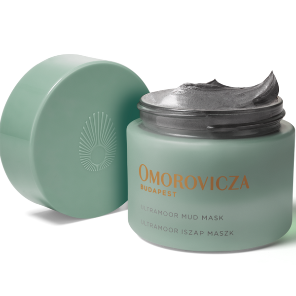 A jar of Omorovicza Budapest Ultra-Hydro Mud Mask with its lid off, showing the gray mask cream inside, on a white background.