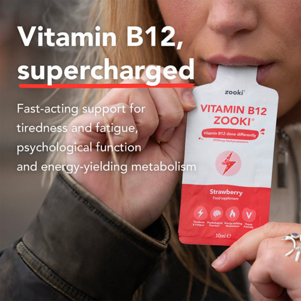 Person holding a Zooki Vitamin B12 supplement packet with text about its benefits.