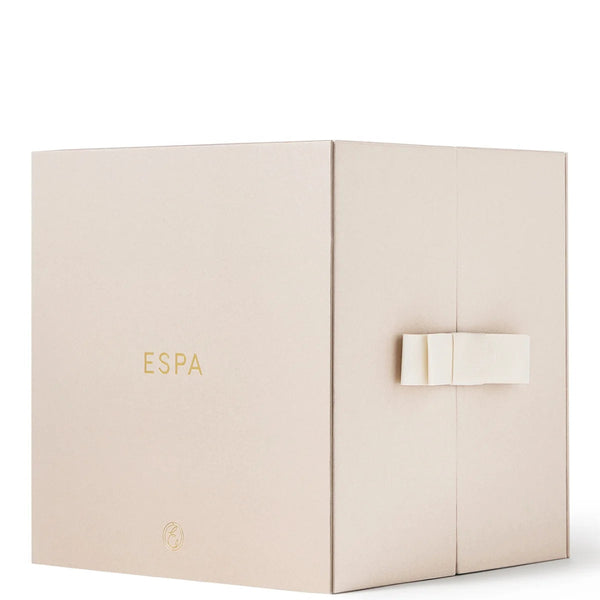 A square beige gift box with the brand name 'ESPA' printed in gold on the front, featuring a small gold emblem near the bottom and a white ribbon tied around the right side, set against a plain white background.