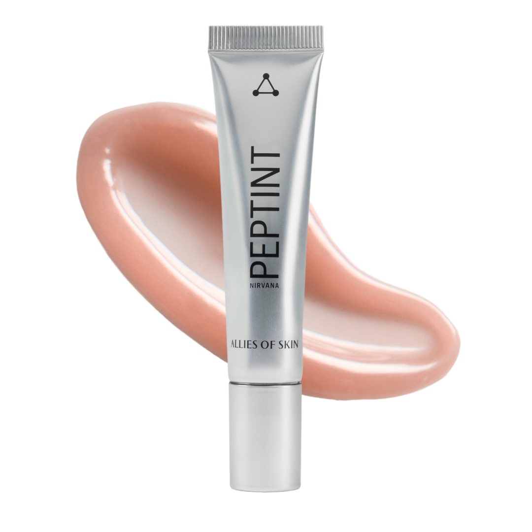 A silver squeeze tube of PEPTINT by Clés de Skin, set against a glossy peach-colored cosmetic swatch on a solid white background.