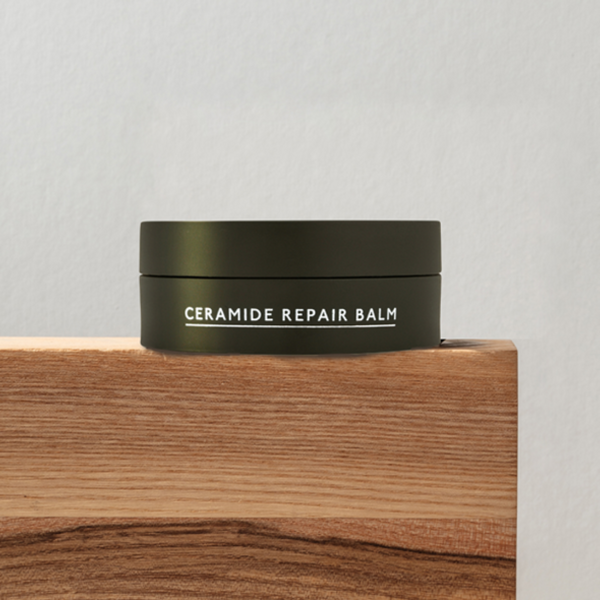 Ceramide repair balm container on a wooden surface with a gray background