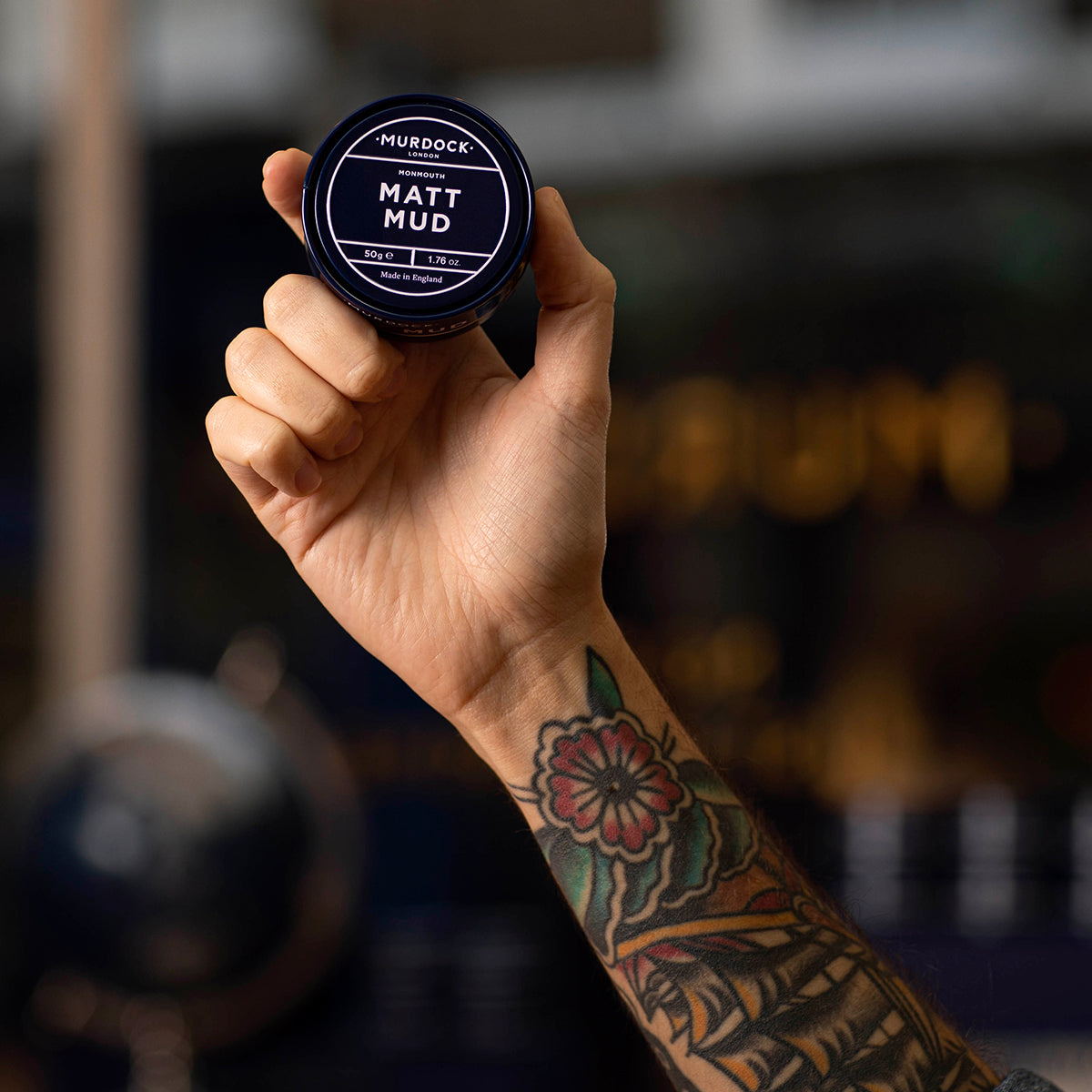 a tattooed hand holding the Murdock London Matt Mud tub into the air