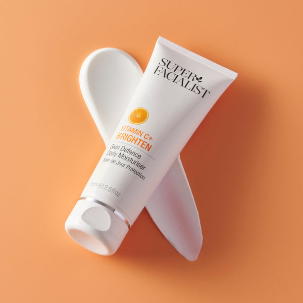 Daily moisturiser tube diagonally placed on orange background  and diagonal cream swatch