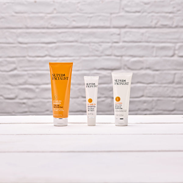 Vitamin C daily polish wash and skin serum and daily mosituriser on white table and white brick background wall